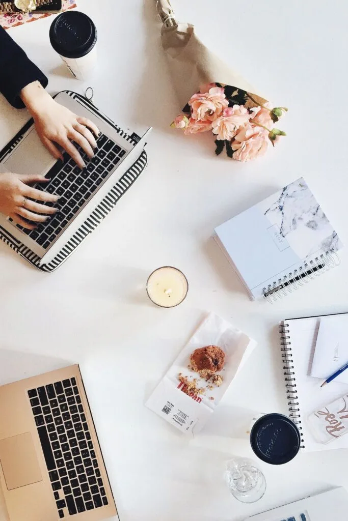 hands typing on a computer with items around the desk